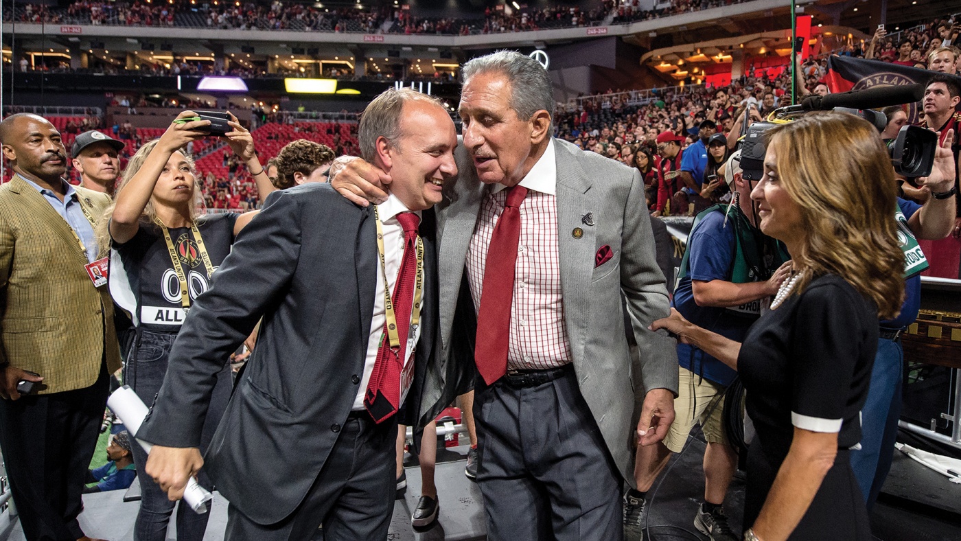 Photograph of Darren Eales &rsquo;95 hugging Falcons and Atlanta United owner Arthur Blank in a stadium